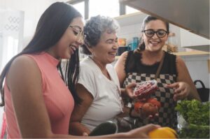 Three women are smiling as they cook together 