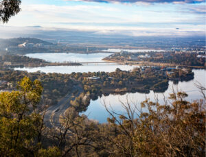 Photograph of Lake Burley Griffin taken from a high point - woody shores and parliamentary triangle visible. Peaceful and beautiful. 